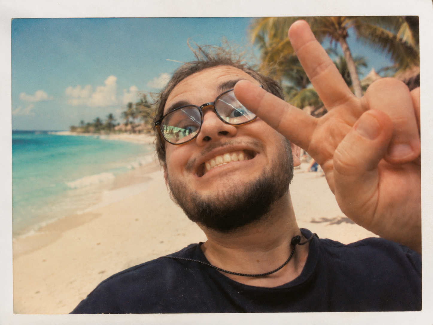 Mitchell Hynes smiling on a beach and holding up a peace sign